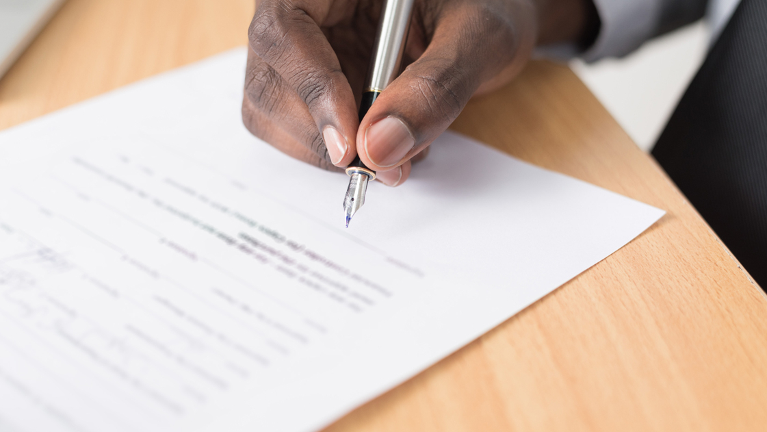 Picture of a man signing a document for society MDPI affiliations program.