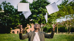 Academic goals achieved! A man throws his papers in the air.
