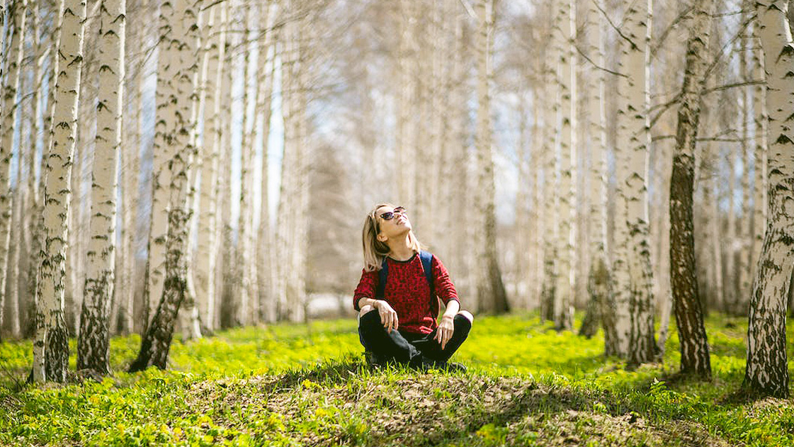 Ecofeminism demonstrated with an image of a woman sat on the grass.