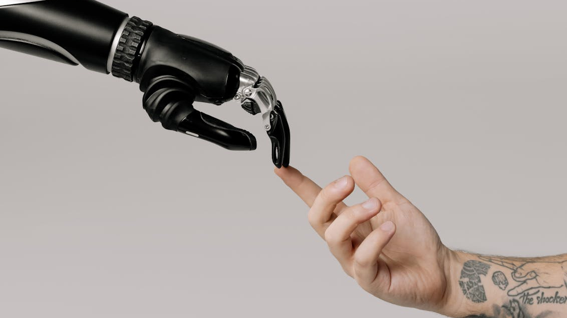 A robot hand and a human hand touching to represent AI