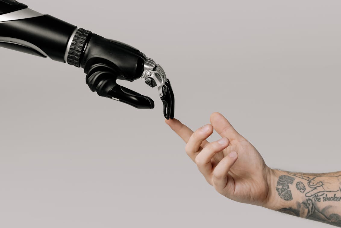 A robot hand and a human hand touching to represent AI