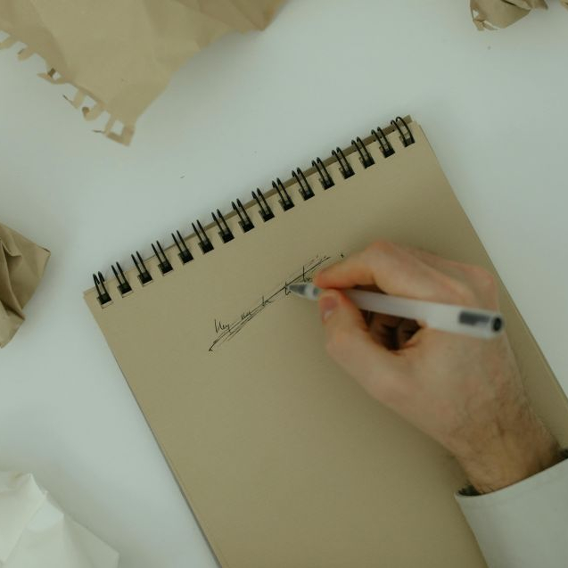 A man writing on a piece of paper then crossing it out indicating phrases to avoid in academic writing
