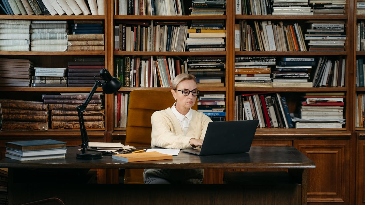 Librarian working at her computer with rows of books behind her desk.