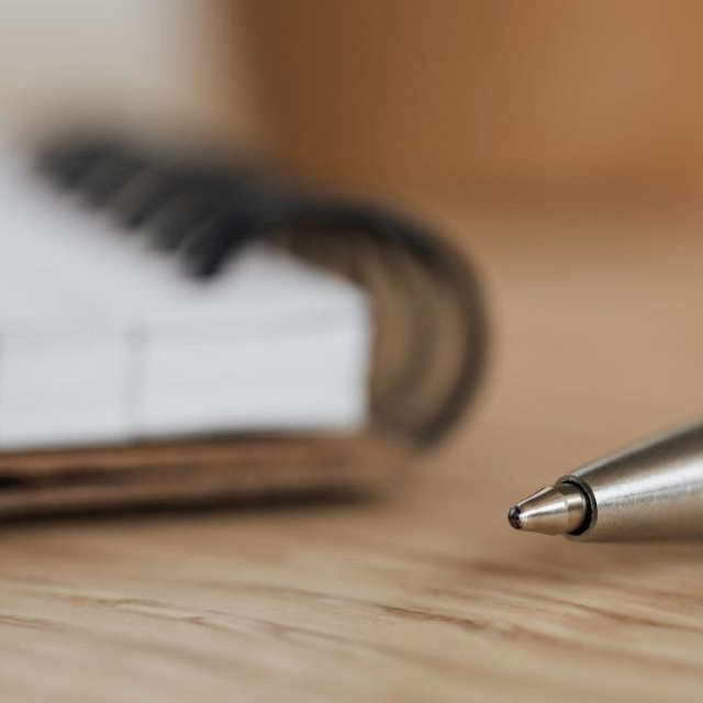 A pen ready to write out conjunctions on a piece of paper.