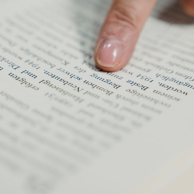 A finger pointing at text in a book.